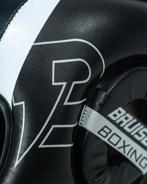 Enfoque detallado lateral izquierdo casco Bruiser negro. Raya blanca y logo de la marca.