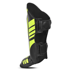 Parte lateral de espinilleras de kickboxing y muay thai, negras con detalles verde neón, diseño anatómico con protección para espinilla y empeine y cierre ajustable para entrenamiento y sparring.