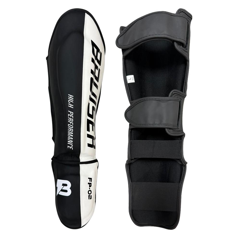 Espinilleras de boxeo y muay thai negras y blancas. Logo Bruiser en la parte frontal lateral. Relleno de alta densidad que absorbe golpes y protege espinillas. Sistema de velcro reforzado para entrenamiento de contacto. Imagen frontal.
