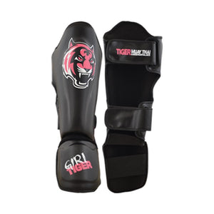 Espinilleras marca Tiger color negro con detalles en rosa por delante y por detrás. Logo en el centro. Hechas de piel sintética con doble cierre de velcro. Neopreno en tibia y empeine.
