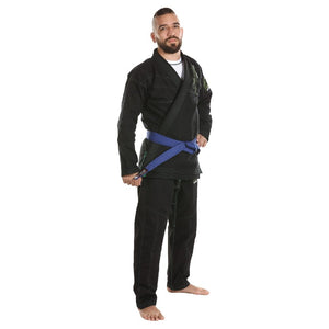 Kimono de Jiu Jitsu color negro con detalles verdes, llevado por modelo con brazo izquierdo en la cadera. Logo de "Bruiser" bordado en la manga izquierda. Atado con cinturón azul. Hecho de-100% algodón, ajuste perfecto. Imagen lateral.
