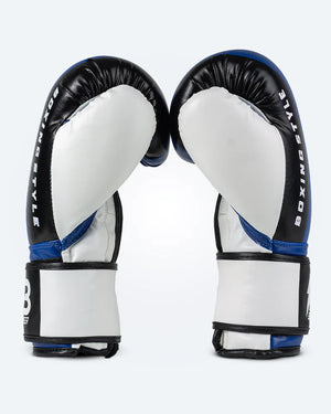 Par de guantes de boxeo negros con blanco, para muay thai y kick boxing con cierre velcro seguro. Imagen lateral.