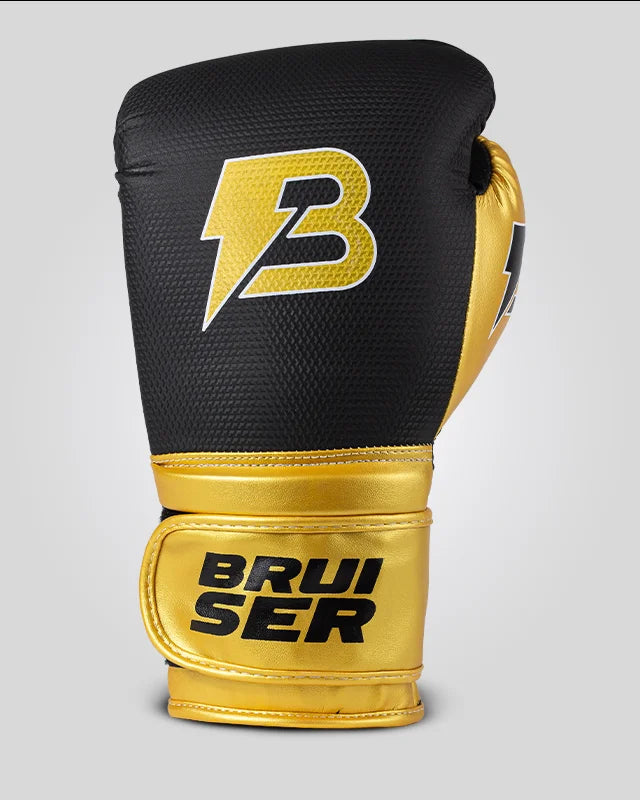 Guantes de boxeo de piel sintética, negros con detalles dorados y logo central, para muay thai, kick boxing y entrenamiento de contacto. Imagen frontal.
