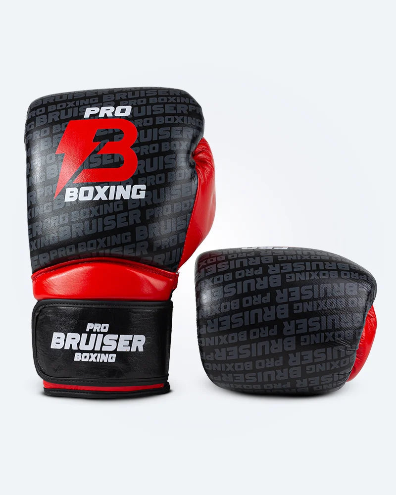 Guantes de boxeo Bruiser color negro y rojo con detalles en blanco uno de pie y otro estirado. Logo en el centro. Hechos de piel de vacuno con multicapa absorbente. Cierre de velcro seguro. Imagen frontal.
