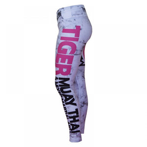 Mallas "TMT" color blanco con detalles negros y rosas. Logo en grande de color rosa en pierna izquierda. Hechas de poliester y spandex. Cordón de ajuste de cintura. Perfi izquierdo.