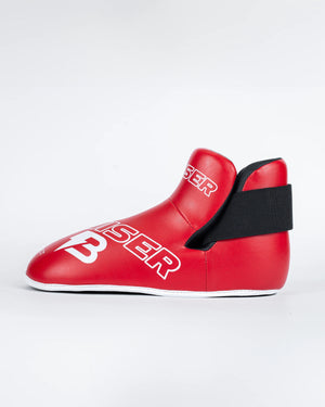 Protectores de pie "Bruiser" color rojo para kickboxing, taekwondo o muay thai. Hechos de polipiel Sistema de sujeción con elástico y cierre de velcro. Perfil izquierdo.