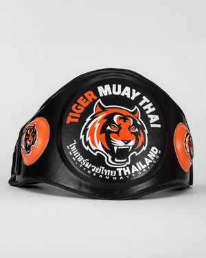 Ventral "TMT" color negro y naranja con logo en grande en la parte frontal. Hecho con materiales premium y relleno de alta densidad. Ajuste cómodo y natural, velcro reforzado. Imagen frontal.
