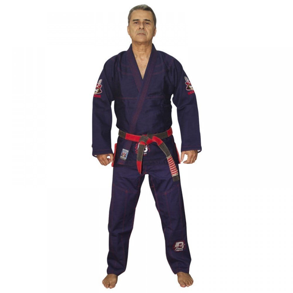 Kimono de Jiu Jitsu color azul marino con detalles rojos, llevado por modelo con brazos estirados y cinturón rojo y negro. Diseño bordado en las dos mangas y logo de "Bruiser" en parte inferior. Hecho de 100% algodón, ajuste perfecto. Imagen frontal. 