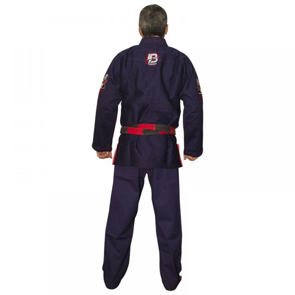 Kimono de Jiu Jitsu color azul marino con detalles rojos, llevado por modelo de espaldas con brazos estirados y cinturón rojo y negro. Diseño bordado en las dos mangas y logo de "Bruiser" en parte superior trasera. Hecho de 100% algodón, ajuste perfecto. Imagen trasera. 