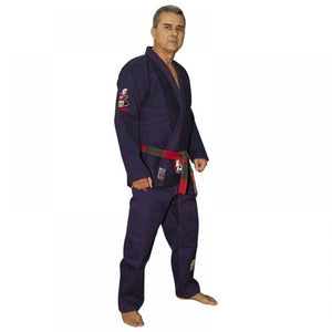 Kimono de Jiu Jitsu color azul marino con detalles rojos, llevado por modelo con brazos estirados y cinturón rojo y negro. Diseño bordado en las dos mangas y logo de "Bruiser" en parte inferior. Hecho de 100% algodón, ajuste perfecto. Imagen lateral. 