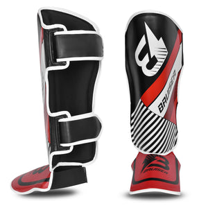 Espinilleras de kickboxing y muay thai rojas y negras con detalles blancos y logo Bruiser en la parte frontal, hecha de piel sintética con relleno de alta densidad que absorbe golpes y protege espinillas y sistema de velcro reforzado para entrenamiento de contacto. Imagen frontal.