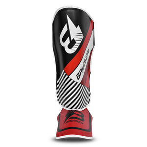 Espinillera de kickboxing y muay thai roja y negra con detalles blancos y logo Bruiser en la parte frontal, hecha de piel sintética con relleno de alta densidad que absorbe golpes y protege espinillas y sistema de velcro reforzado para entrenamiento de contacto. Imagen frontal.