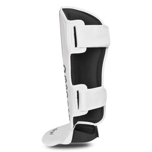 Espinillera de Muay Thai marca Bruiser por delante y por detrás color blanco con detalles azules y rojos. Hecha de polipiel con cresta acolchada y protector de pie. Empeine de neopreno y cierre de velcro seguro. Perfil izquierdo trasero. 