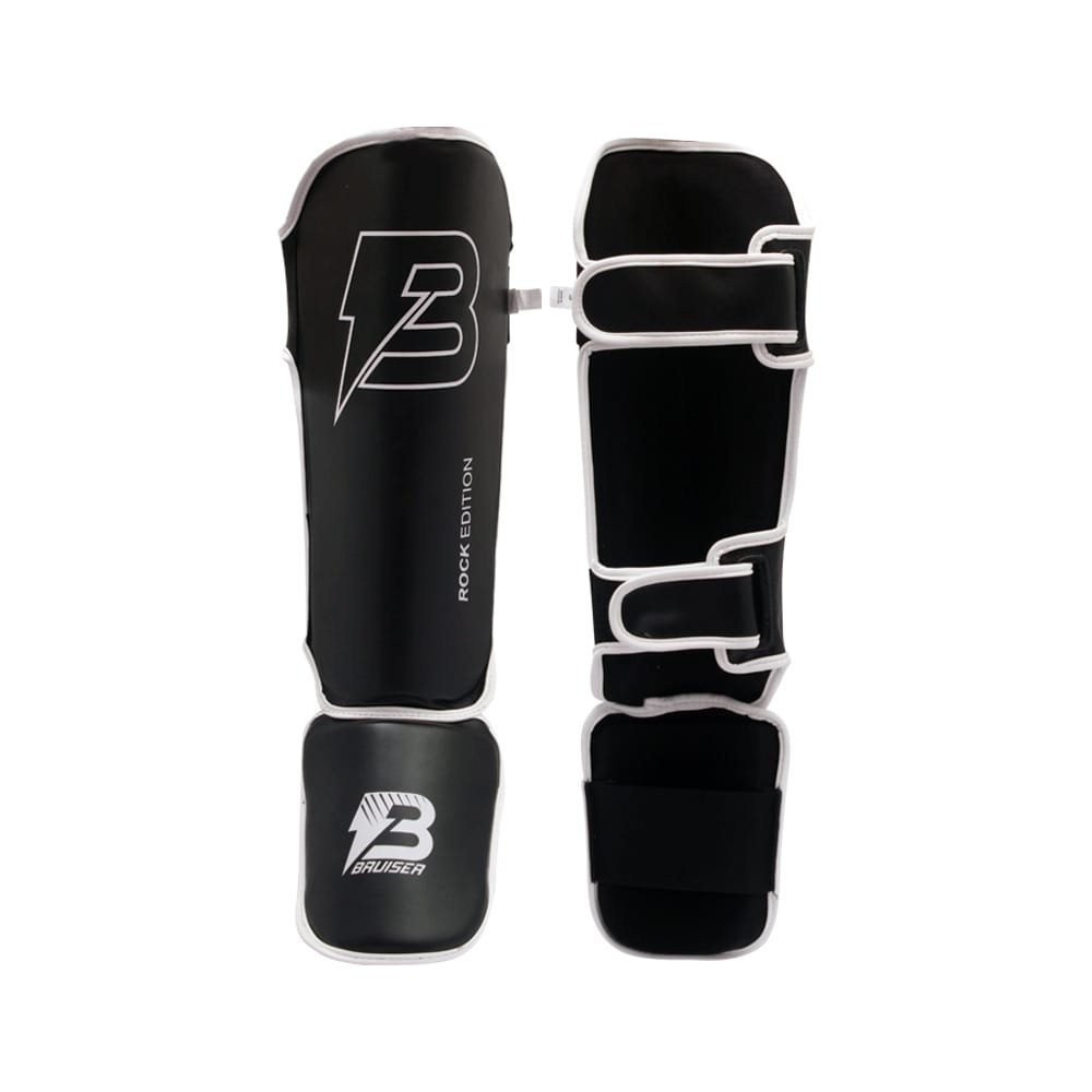 Espinilleras marca Bruiser color negro con detalle blancos. Logo en el centro y empeine. Hechas de polipiel con cresta acolchada. Empeine de neopreno con sistema de velcro reforzado. Imagen frontal. 