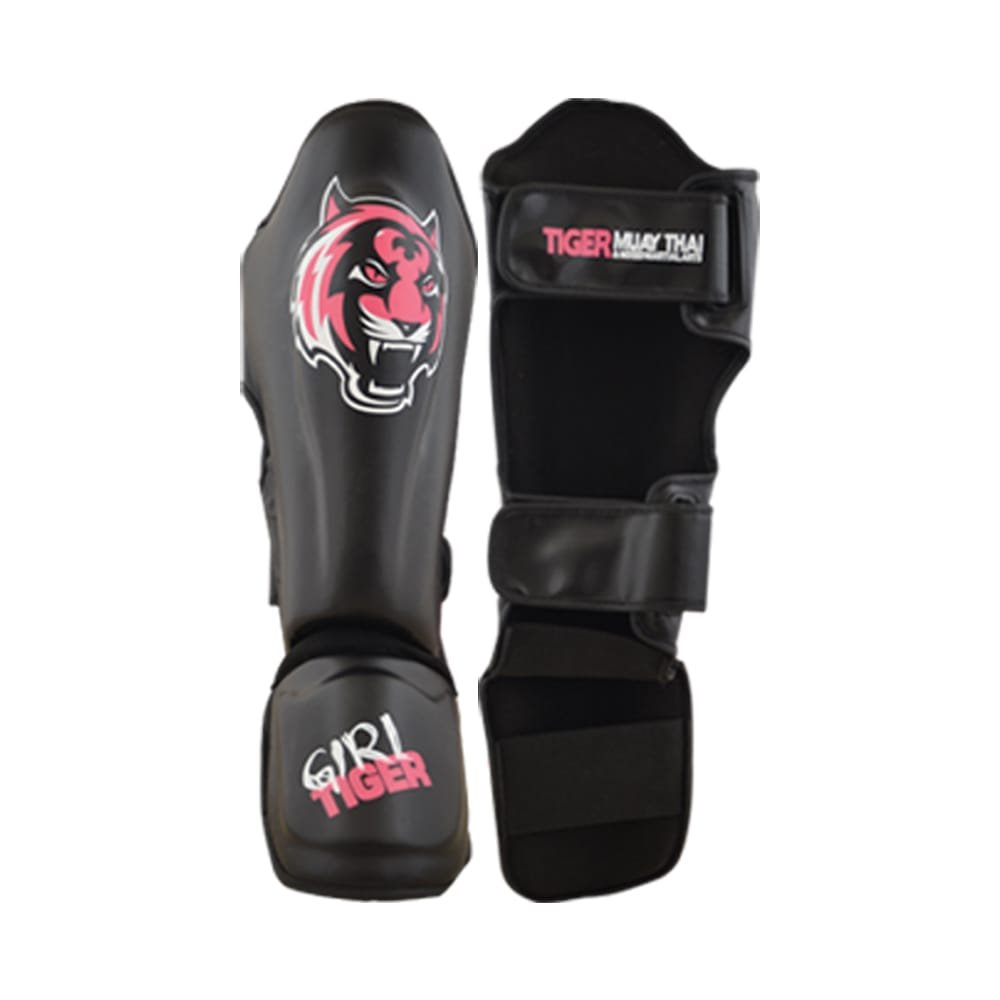 Espinilleras marca Tiger color negro con detalles en rosa por delante y por detrás. Logo en el centro. Hechas de piel sintética con doble cierre de velcro. Neopreno en tibia y empeine. 