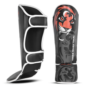 Espinilleras marca Tiger para niños por delante y por detrás color negro y naranja. Logo en el centro. Hechas de polipiel con espuma absorbente. 