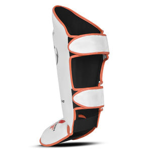 Espinillera marca Tiger por detrás color blanco y naranja. Logo en el centro. Hechas de polipiel con espuma absorbente. Perfil izquierdo.
