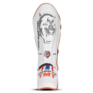 Espinillera marca Tiger por color blanco y naranja. Logo en el centro. Hechas de polipiel con espuma absorbente. Imagen frontal. 