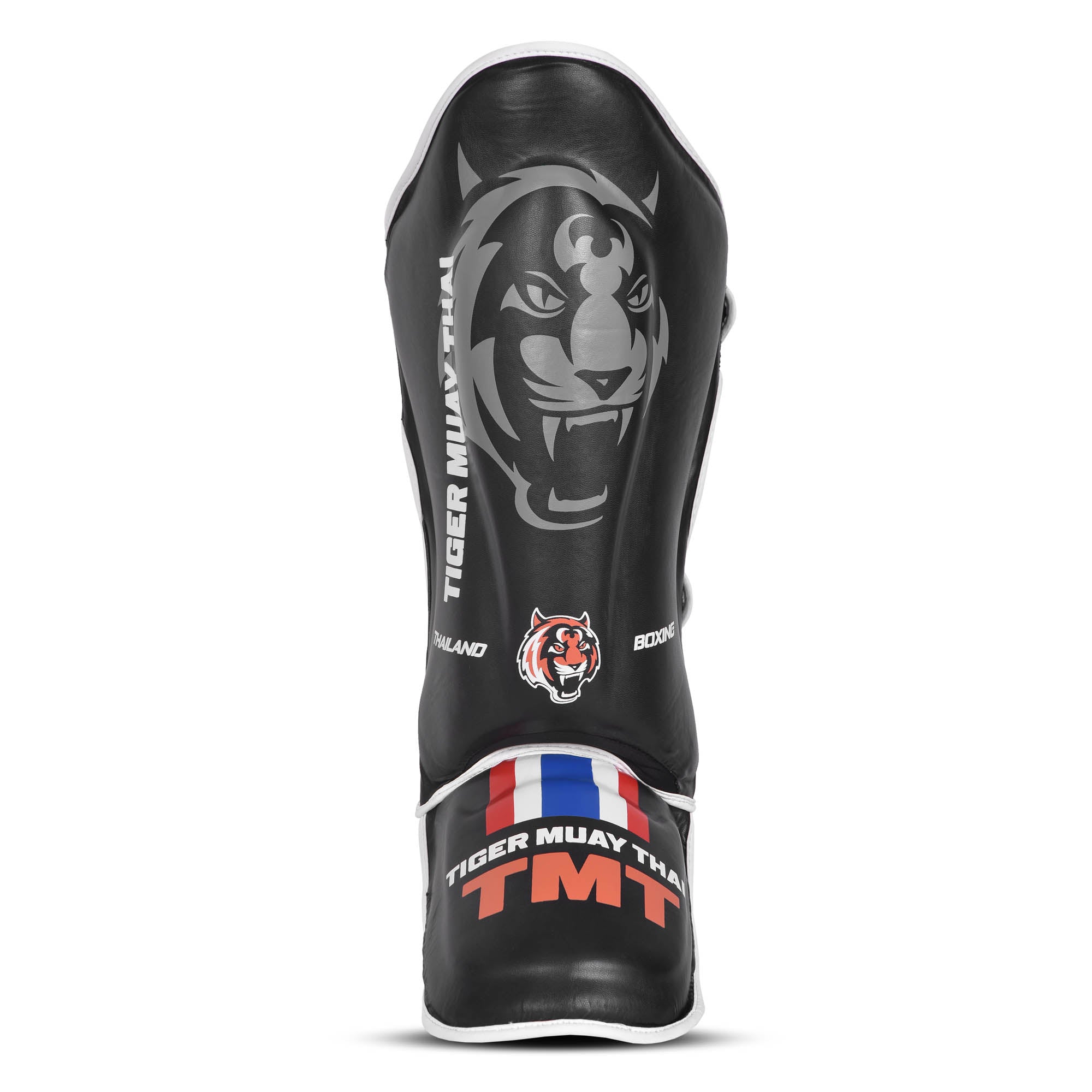Espinillera Tiger Muay Thai color negro con detalle naranjas. Logo de la marca en el centro. Hecha de polipiel con refuerzo en tibia y pie y espuma absorbente. Imagen frontal. 