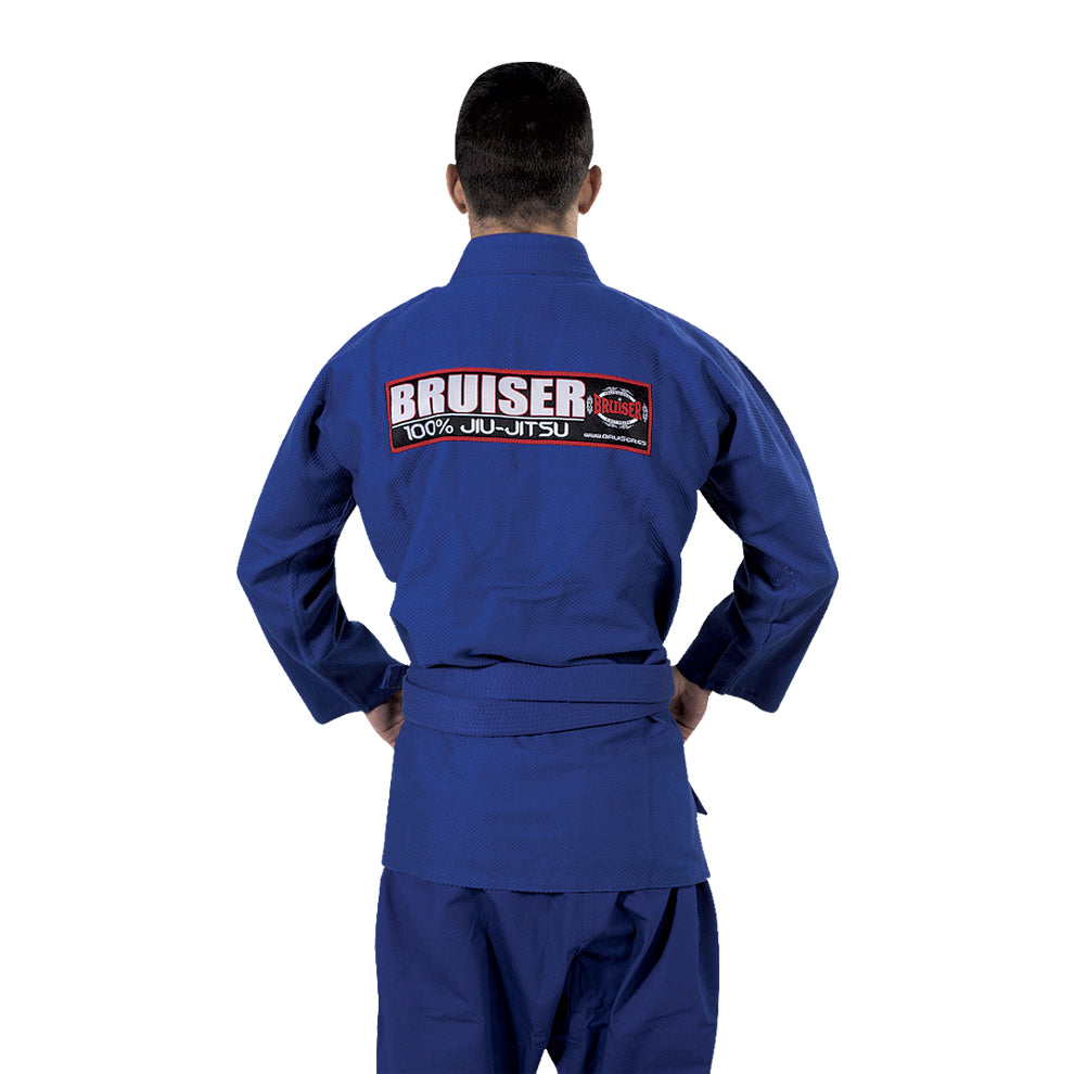 Parte trasera de Kimono de Brazilian jiu jiitsu con cinturón azul, usado por modelo con manos agarradas al cinturón. Parche de "Bruiser" en grande. Tejido resistente pensado para entrenamiento y competición de BJJ y grappling.
