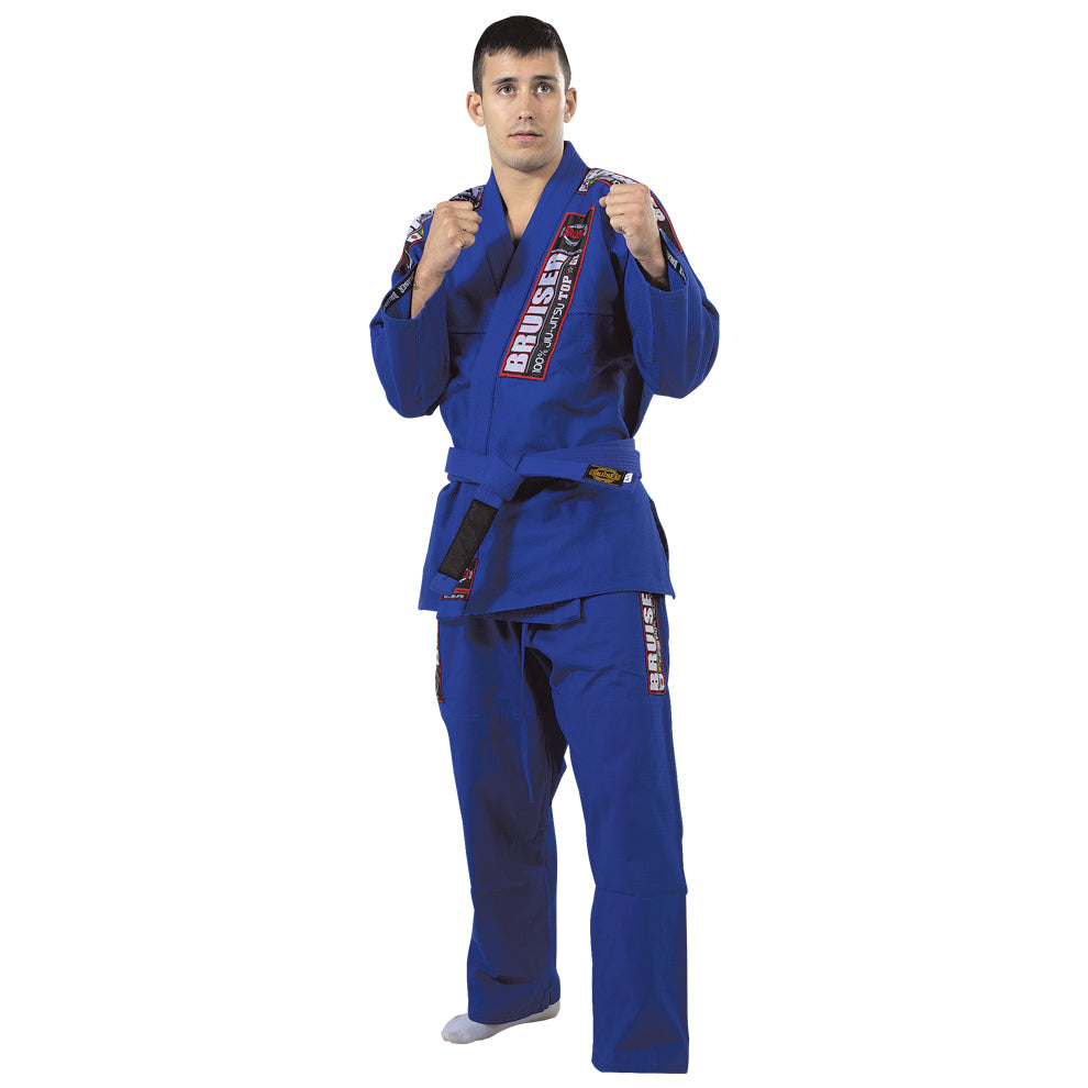 Kimono de Brazilian jiu jiitsu con cinturón azul, usado por modelo en posición de combate. Diseño clásico con parches "Bruiser" en chaqueta y pantalón.  Tejido resistente pensado para entrenamiento y competición de BJJ y grappling.

