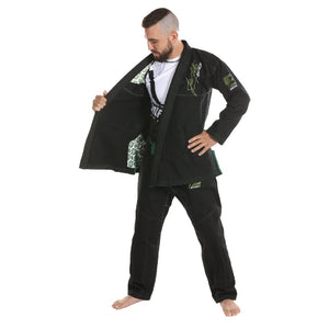 Kimono de Jiu Jitsu color negro con detalles verdes, llevado por modelo con brazo izquierdo en la cadera y con el otro semiabriendo el traje, rashguard por dentro. Logo de "Bruiser" bordado en la manga izquierda. Hecho de-100% algodón, ajuste perfecto. Imagen frontal abierta. 