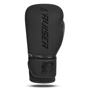 Guante de boxeo "Bruiser" color negro hecho de polipiel de alta calidad. Logo Bruiser en el centro del guante negro brillante y en velcro. Foto frontal.  
