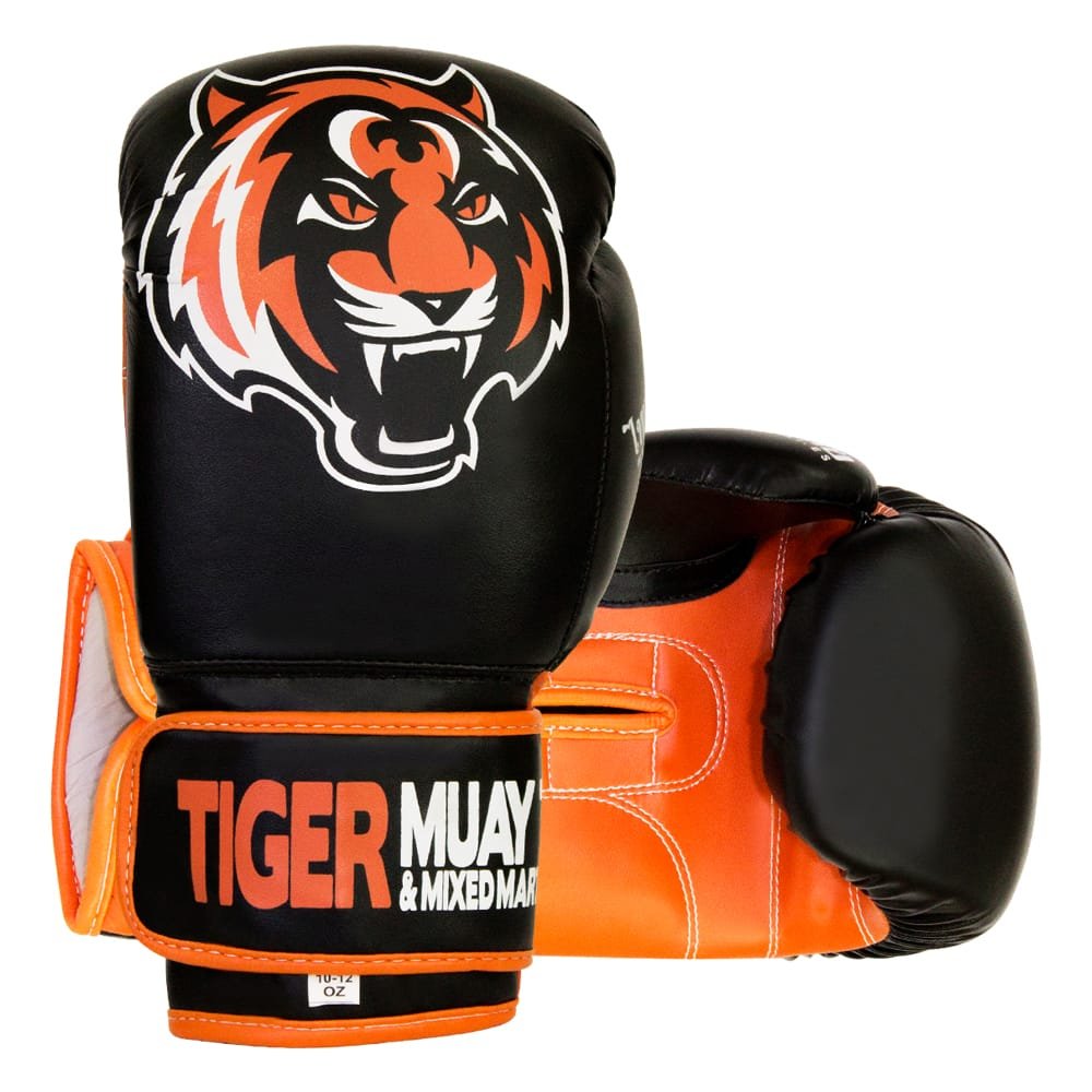 Guantes de boxeo marca Tiger uno de pie y otro estirado color negro y naranja. Logo en el centro. Hechos de piel sintética con capas densas. Cierre de velcro rígido y cuerda interior ara mejor sujeción. 