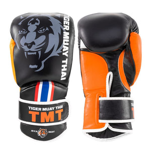 Guantes de Muay Thai marca Tiger por delante y por detras color negro y naranja. Logo Tiger en el centro. Hechos de piel de vaca con relleno en Flex. Velcro seguro. Imagen frontal. 
