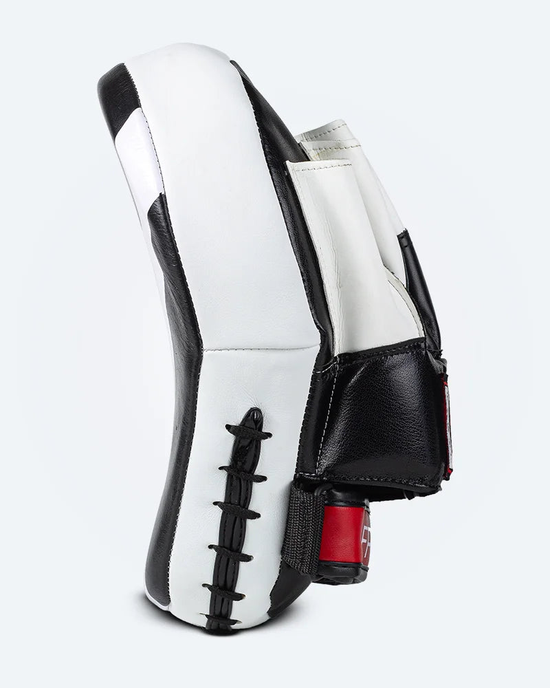 Perfil izquierdo manopla curvada marca Bruiser color negro y blanco.  Hecha de cuero con acolchado de espuma denso. Palmas acolchadas y bola de agarre. Bolsillo de cuero para la mano. 