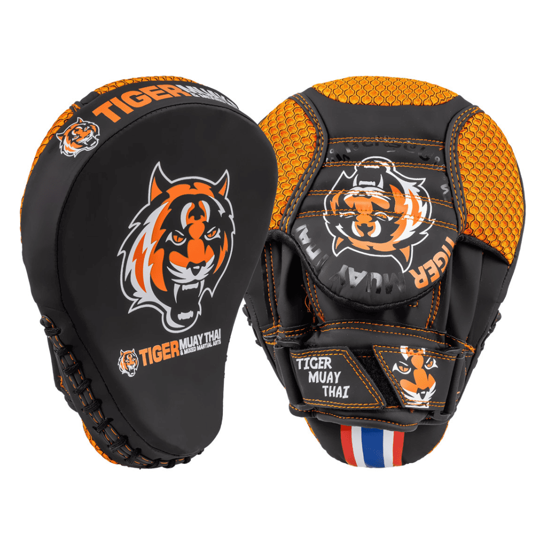 Manaoplas marca Muay Thai por delante y por detrás color negro y naranja. Logo en el centro. Hechas de cuero sintético. Respaldo de malla con correa. Para kickboxing, karate muay thai kick, sparring, dojo, artes marciales, cardio.