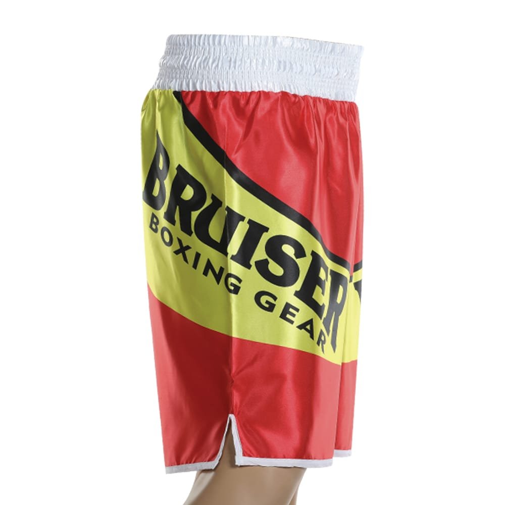 Pantalón deportivo de boxeo Bruiser color rojo, amarillo y blanco llevado por cintura de maniquí. Logo escrito "Bruiser Boxing" a los lados y en cinta superior. Hecho de poliester de alta calidad. Diseñado con corte ideal para la práctica de boxeo. Imagen lateral. 
