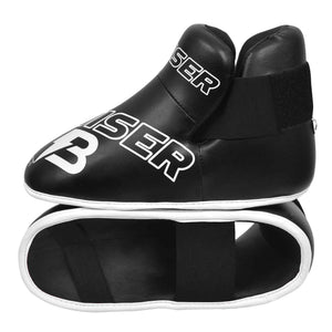 Protectores de pie "Bruiser" color negro para kickboxing, taekwondo o muay thai uno encima del otro. Hechos de polipiel. Sistema de sujeción con elástico y cierre de velcro. Perfil izquierdo.