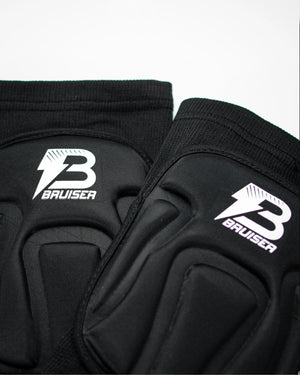 Par de rodilleras Bruiser de color negro. Una detrás de otra. Logo en el centro. Protección, comodidad y libertad de movimiento seguras. Para sparring, BJJ y MMA. Imagen frontal.