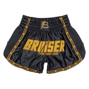 Pantalón corto de Muay Thai marca Bruiser color negro y dorado. Logo en el centro. Hecho de poliéster. Imagen frontal. 