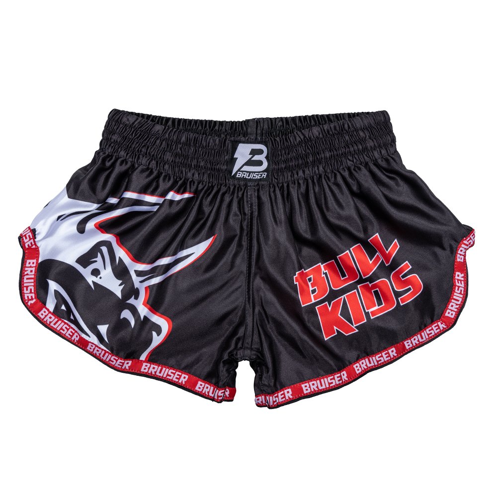 Pantalón corto infantil de Muay Thai marca Bruiser color negro con detalles rojos. Diseño de toro sublimado. Hechos de poliéster. Imagen frontal. 