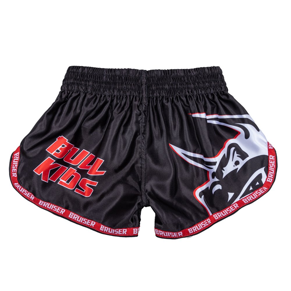 Pantalón corto infantil de Muay Thai marca Bruiser color negro con detalles rojos. Diseño de toro sublimado. Hechos de poliéster. Imagen trasera. 