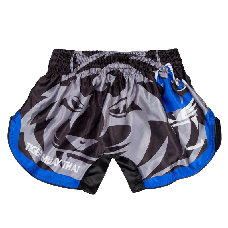 Pantalón corto infantil de Muay Thai marca Tiger color gris y negro con detalles azules. Logo sublimado. Hecho de poliéster. Imagen trasera. 