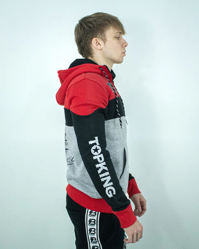 Perfil derecho de sudadera con cremallera y capucha "Top King" color roja, negra y gris, llevada por modelo con brazos estirados. Logo "Top King" en manga derecha escrito en letras blancas.
