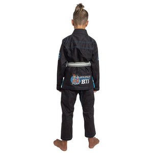 Kimono de Jiu Jitsu "JÚNiOR" negro con detalles azules, llevado por modelo de espaldas con brazos estirados y cinturón gris y blanco. Diseño logo bordado en parte inferior. Hecho de 100% algodón, ajuste perfecto. Imagen trasera.